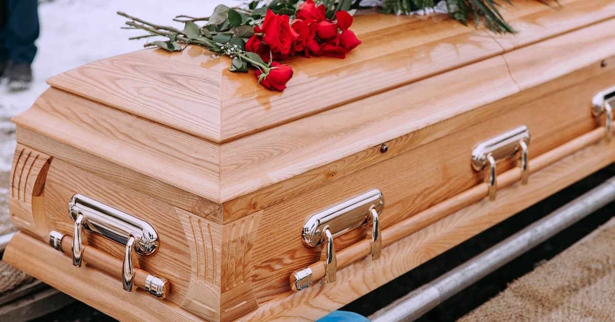 A casket with red roses on top. | Studinski Law